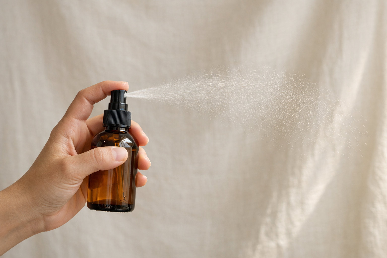 Hand holding mist bottle against natural light